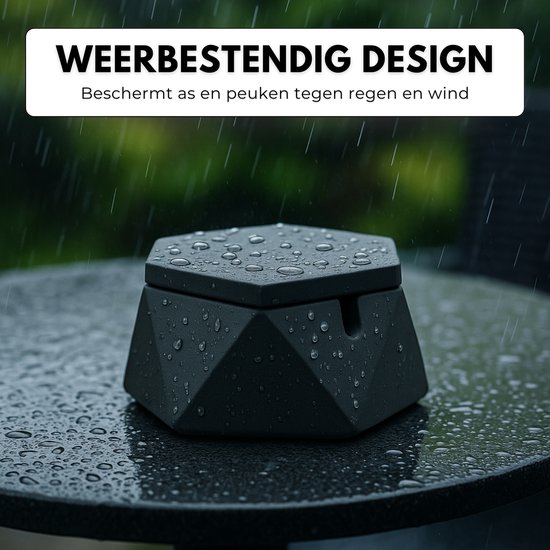 Zwarte, zeshoekige asbak met deksel, nat van de regen op een tuintafel. Tekst: WEERBESTENDIG DESIGN.