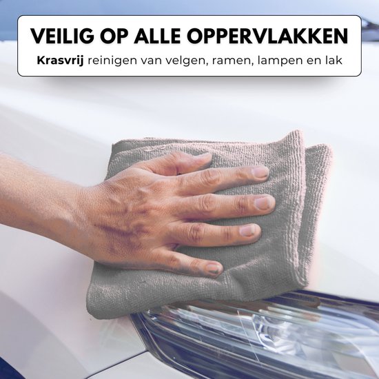 Een hand met een grijze microvezeldoek die de koplamp van een witte auto poetst.