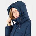 Jonge vrouw met een donkerblauwe, gewatteerde winterjas met capuchon. Ze trekt de capuchon dichterbij.