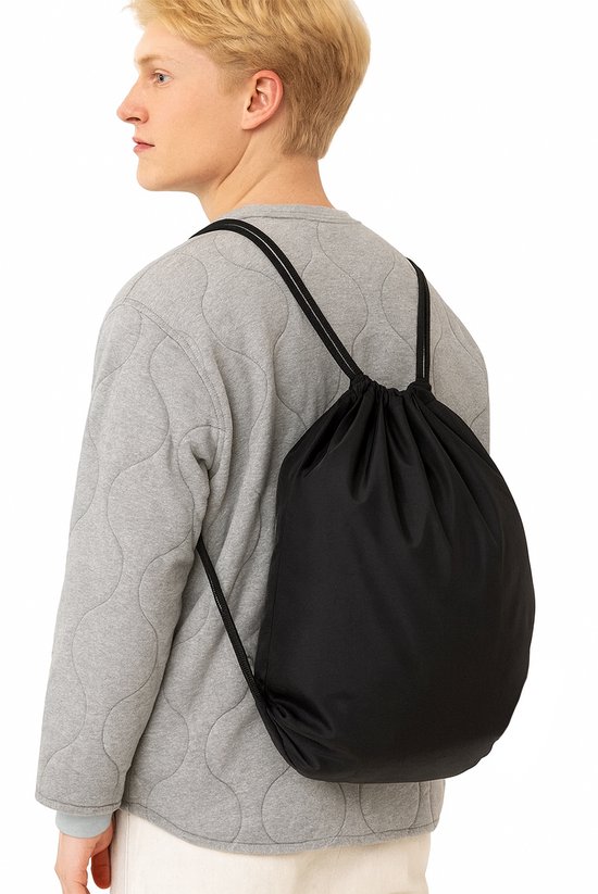 Man met blond haar draagt een zwarte gymtas met trekkoord over zijn schouder.