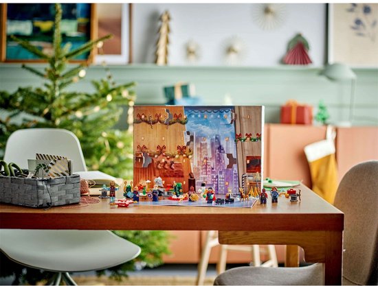 LEGO Marvel Avengers adventskalender op tafel met kerstboom en minifiguren, met kerstversiering op de achtergrond.