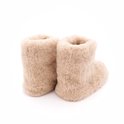 Hoge beige wollen sloffen met bruine zolen, van de zijkant gezien.