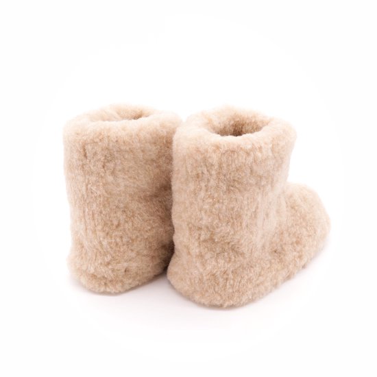 Hoge beige wollen sloffen met bruine zolen, van de zijkant gezien.