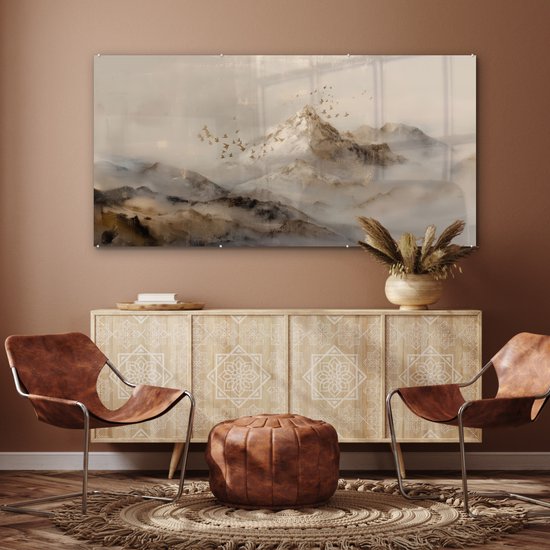 Glazen schilderij van een mistig berglandschap met goudkleurige penseelstreken en vliegende vogels, hangend boven een dressoir in een woonkamer.