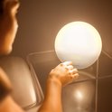 Een hand raakt de Philips wek-up light aan die een warme zonsopkomst nabootst en 09:30 weergeeft.
