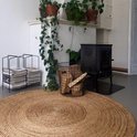 Rond jute vloerkleed in een sfeervolle woonkamer bij de houtkachel.