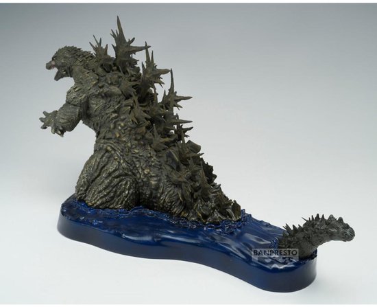 Grijze Godzilla figuur met scherpe rugplaten, knielend op een blauwe waterbasis met logo.