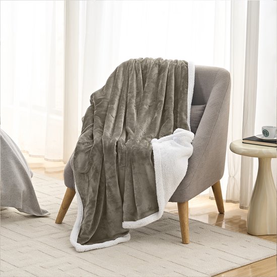 Taupe fleece plaid met witte sherpavoring, gedrapeerd over een fauteuil.