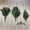 Onderdelen van de kunstkerstboom, inclusief drie secties, metalen standaard en bevestigingsogen.