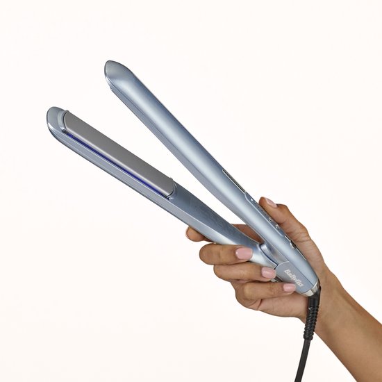 Hand die een lichtblauwe BaByliss stijltang vasthoudt tegen een witte achtergrond.