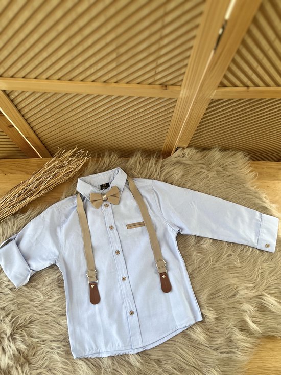 Lichtblauw overhemd met beige vlinderdas en bretels, gecombineerd met beige broek.