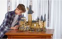 Jongen kijkt naar een grote LEGO Harry Potter Zweinstein Kasteel set met minifiguren.