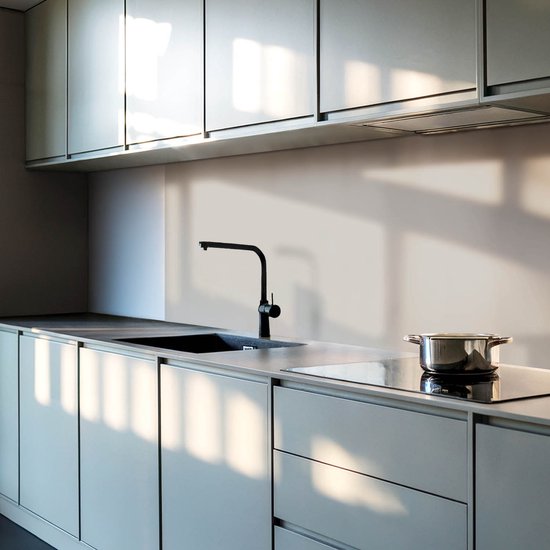 Moderne keuken met lichtgrijze kasten en aanrecht, een zwarte kraan en inductiekookplaat.