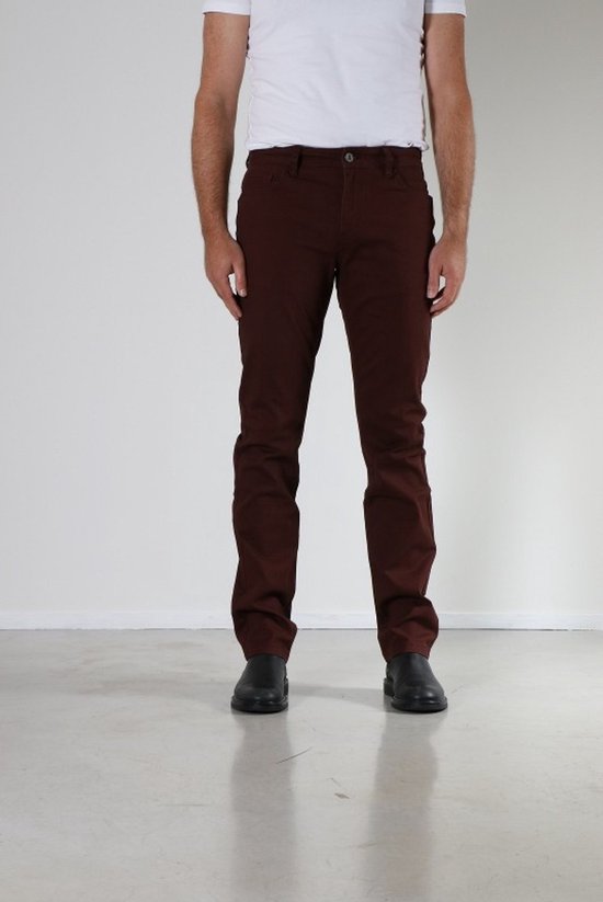 Voorkant van een man in een bordeauxrode broek met een witte t-shirt en zwarte schoenen.