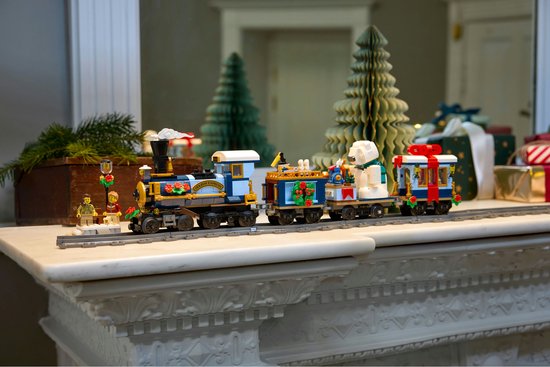 LEGO Feestelijke Kersttrein op een schoorsteenmantel, met kerstboom en cadeaus op de achtergrond.