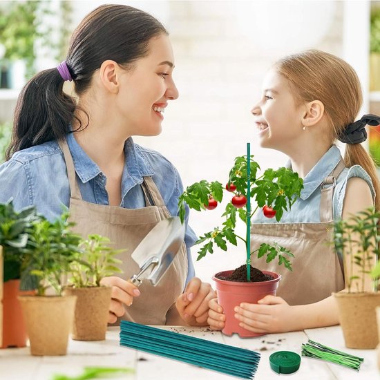 Vrouw en kind tuinieren samen met groene plantensteunen voor een tomatenplant in een pot.