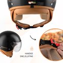 Close-up van de snelsluiting van een zwarte scooterhelm met bruine voering.