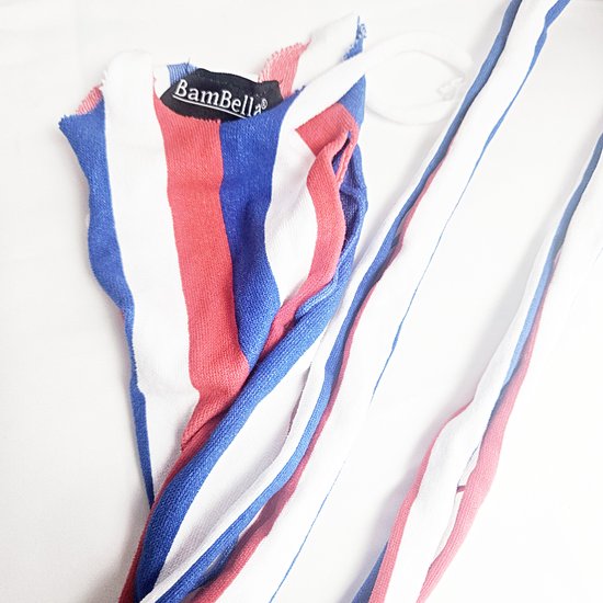Tissu blanc, rouge et bleu rayé de BamBella, plié sur un fond blanc.