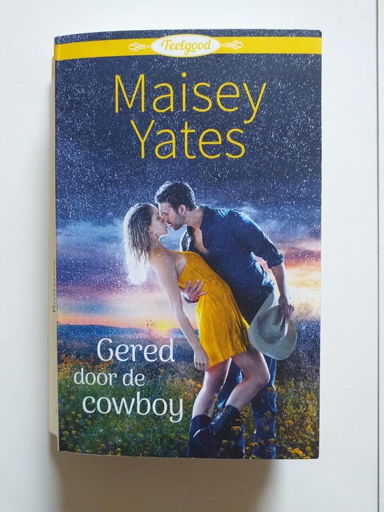 Boekomslag met stel dat elkaar kust in de regen. Een cowboy met hoed in gele jurk en man in blauw shirt. Titel: Maisey Yates Gered door de cowboy. Feelgood.