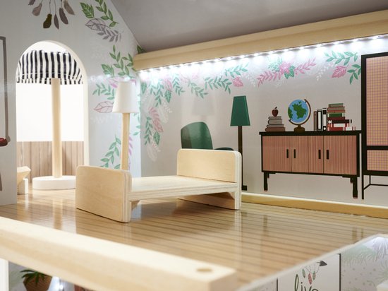 Poppenhuis slaapkamer met houten bed, staande lamp en kast met boeken en een globe. Behang met planten.