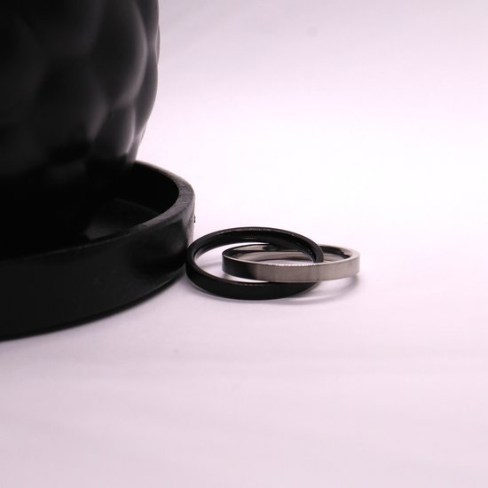 Twee zilverkleurige en zwart matte ringen naast een zwarte schaal.