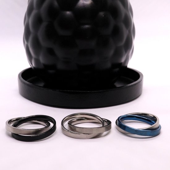 Drie ringen: zwart, zilverkleurig en blauw, naast elkaar op een witte ondergrond.