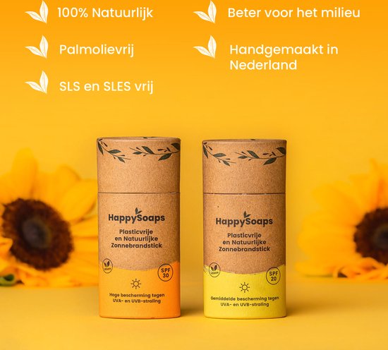 Twee HappySoaps plasticvrije zonnebrandsticks, een met oranje en een met gele opdruk, naast zonnebloemen.