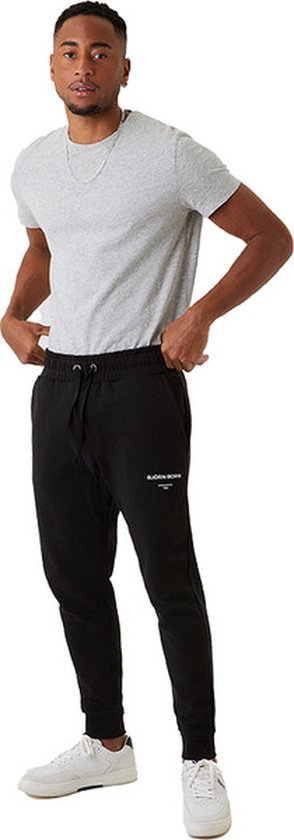 Homme en pantalon de jogging noir Björn Borg, t-shirt blanc et baskets blanches.