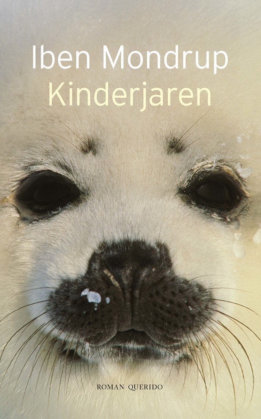 Close-up van een babyzeehond met donkere ogen, een zwart neusje en witte snorharen. De tekst 'Iben Mondrup Kinderjaren' is erop gedrukt.