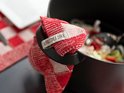 Rood-wit geruite theedoek met label 'Knit Factory' om een zwarte pan.