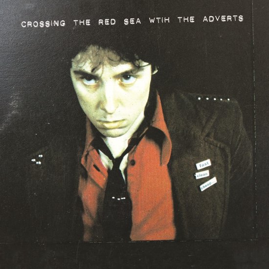 Un homme aux cheveux noirs et une chemise rouge porte une veste cloutée. Au-dessus de l'image, le texte "CROSSING THE RED SEA WTİH THE ADVERTS".