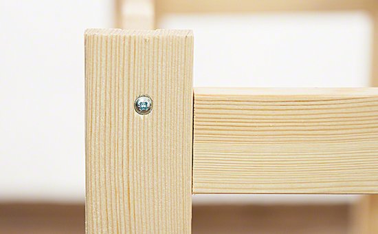 Close-up van een schroef die twee stukken hout van een wijnrek verbindt.