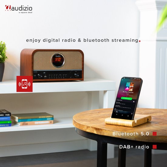 Retro radio met houten afwerking en stoffen voorkant, met telefoon voor Bluetooth streaming.