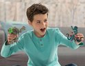 Een jongen met een lichtblauwe trui speelt met een stenen monster en een blauwe octopus figuur.