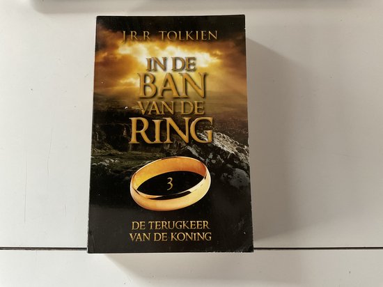 Boekcover 'De ban van de ring: De terugkeer van de koning', met een gouden ring boven een berglandschap.