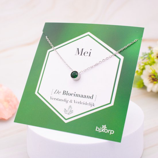 Zilverkleurige ketting met groene zirkonia hanger op een groene kaart met 'Mei De Bloemmaand' erop.