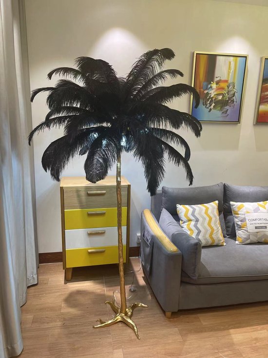 Een staande lamp met een mat gouden poot en grote zwarte veren.