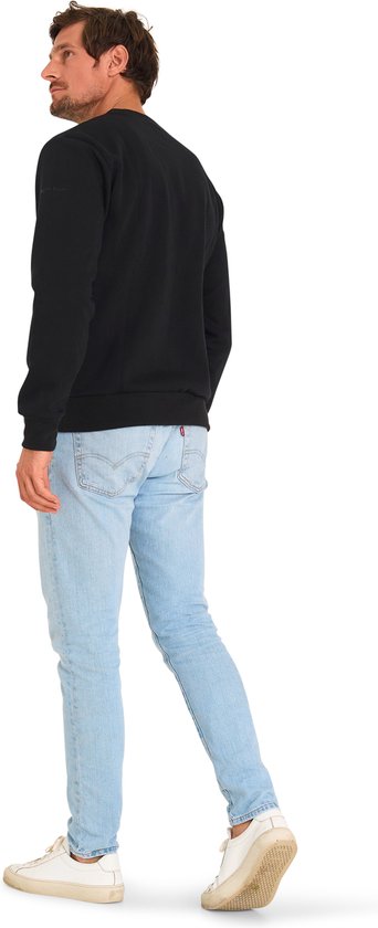 Man van achteren gezien, draagt een zwarte sweater en lichtblauwe jeans.