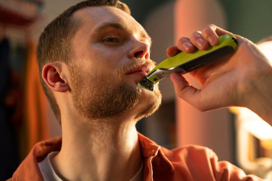 Man met baard en rode trui scheert bovenlip met Philips OneBlade.