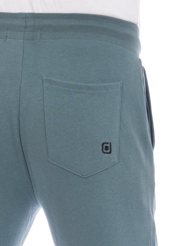 Donkergroene joggingbroek, detail van de achterzak met zwart logo.