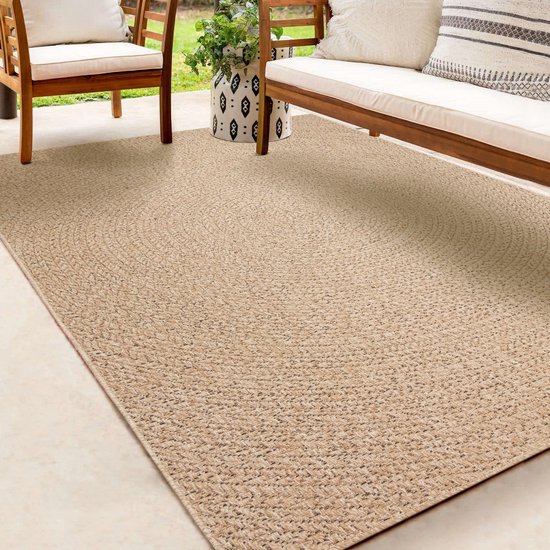 Beige vloerkleed met cirkelpatroon, op een terras met houten meubels.