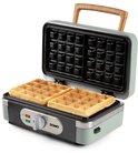 Groene wafelijzer met open deksel, met twee goudbruine wafels erop.