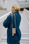 Vrouw met spijkerjack draagt een roze telefoonhoesje met koord om haar nek.