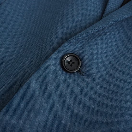Detail van een enkele zwarte knoop op een effen blauwe blazer.