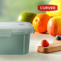 Boîte Curver vert pâle avec couvercle, avec des fruits et des baies en arrière-plan.