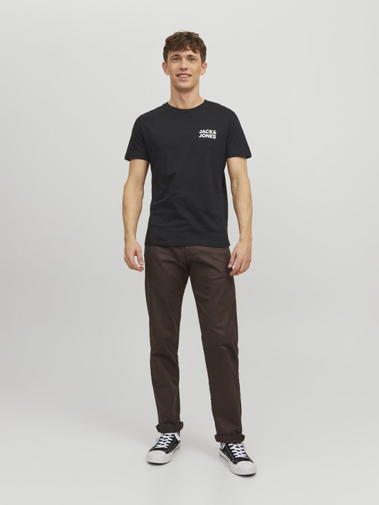 Man met zwarte T-shirt met witte JACK & JONES-opdruk op borst, en bruine broek.