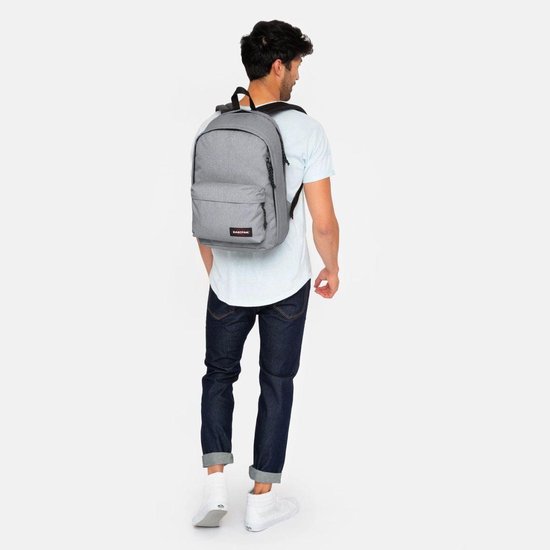 Man met grijze Eastpak rugzak op de rug, kijkend naar rechts.