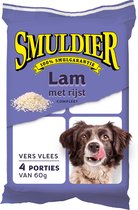 Smuldier Lam met Rijst hondenvoer. 4 porties van 60g. Een hond likt zijn lippen.