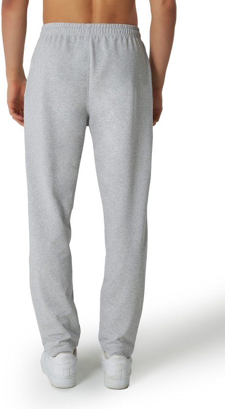 Man van achteren, draagt een grijze joggingbroek met rechte pijpen en witte sneakers.