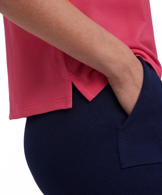 Detail van de zoom van een koraalroze Falke poloshirt, met spleetjes aan de zijkant.